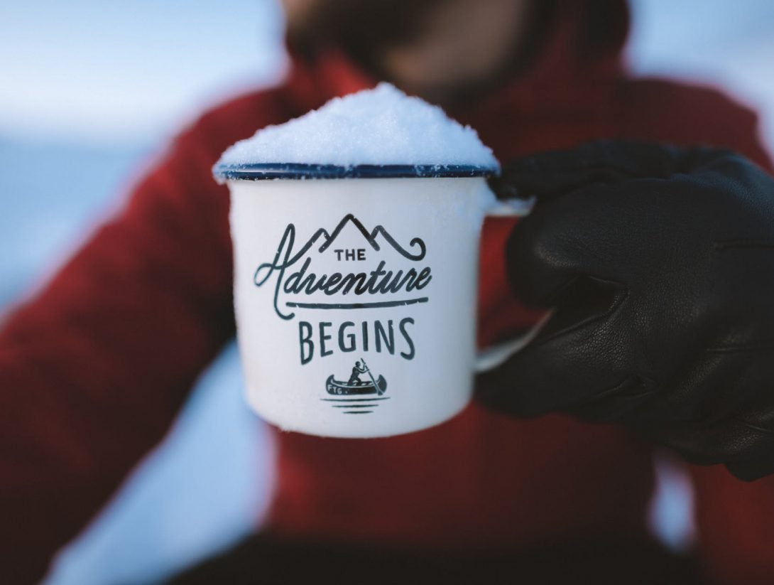 selective focus photography of person holding the adventure begins mug
